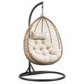 Poltrona sospesa in rattan sintetico con cuscino in poliestere beige e struttura in metallo nero